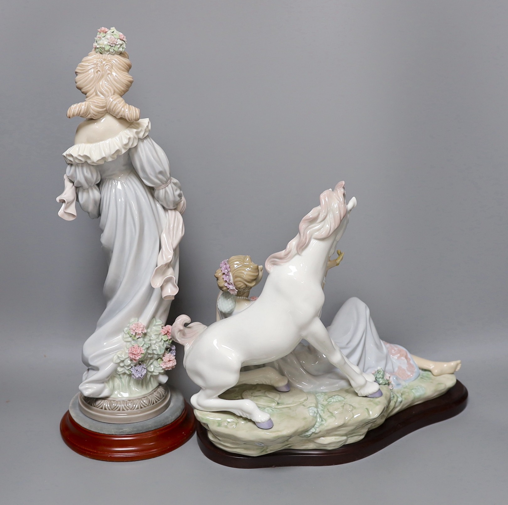 A Lladro figure of a lady and a similar figure group of a lady and a unicorn. Both on hardwood stands, tallest 41cm excluding stand
